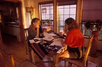 While their Dad sleeps nearby, Renée and Nicolle sort through the ever-growing piles of bills and papers on the dining room table.