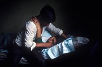 Photograph of husband comforting his dying wife at a remote health clinic in the tiny village of Santa Cruz Barillas, Guatemala. 
