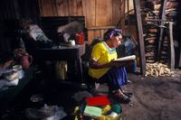 Photograph of crippled Mayan, Lena Matayo, singing hymms in her dirt-floored shack; Santa Cruz Barillas, Guatemala. 