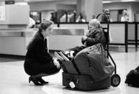 Having just cleared US Customs, Sergei rests atop luggage in the Anchorage Airport<br/>as Krista Atkison, a Russian-speaking airport employee, reassures him.