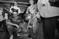 Arriving in Seattle, Sergei cries as he holds the hand of his host mother.